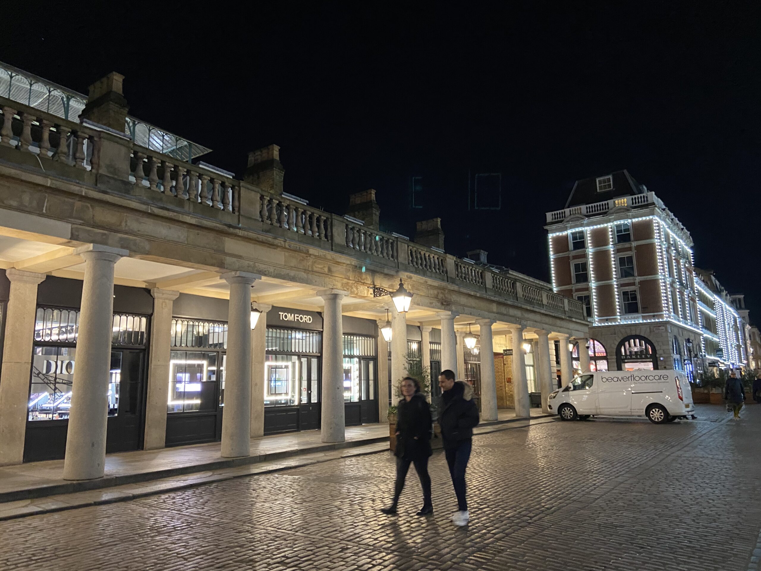 De verlichte colonnade van Covent Garden met luxewinkels 's avonds