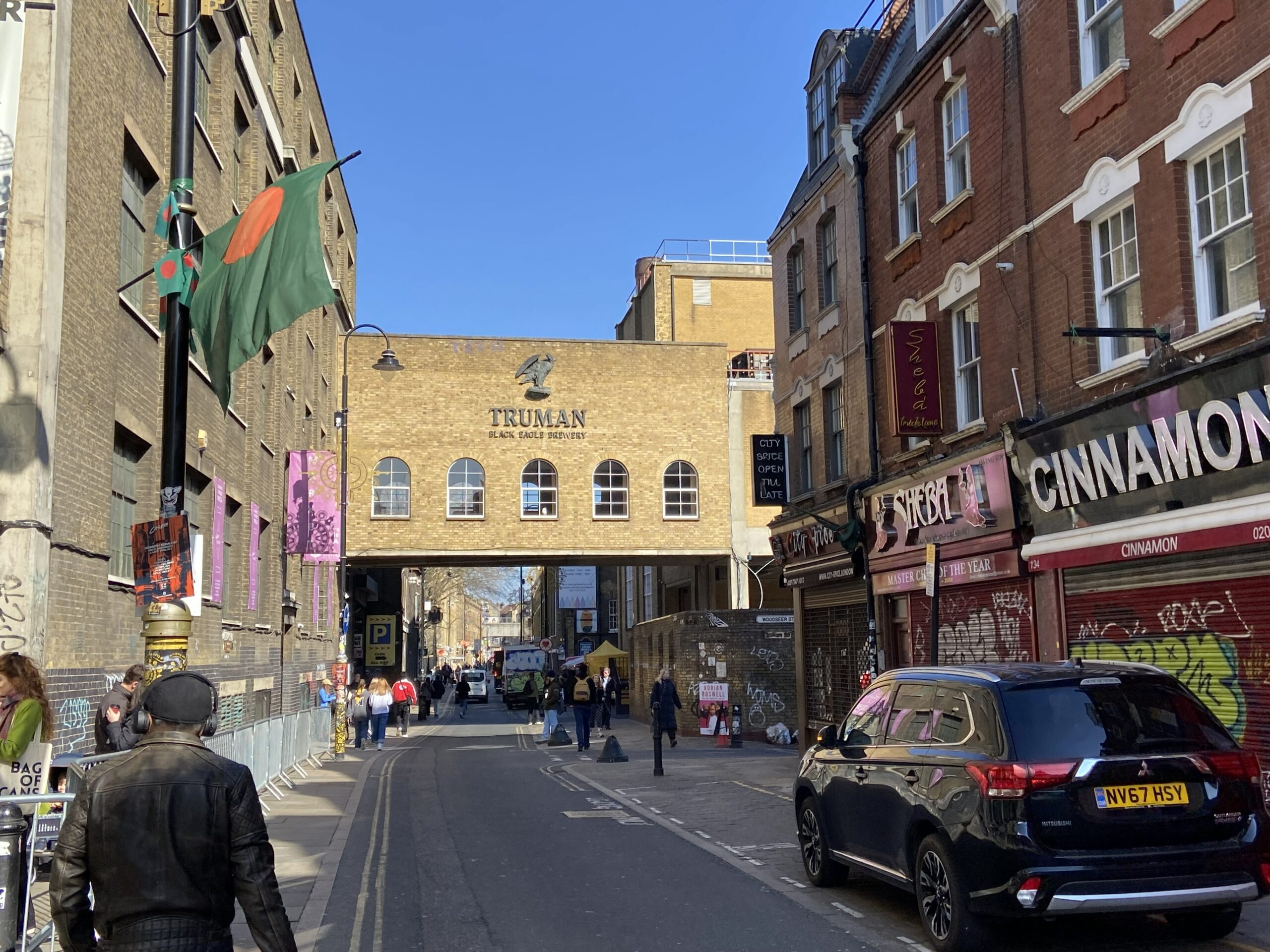 Brick Lane in Shoreditch met de Truman Brewery boog op de achtergrond en de Bangladeshse vlag