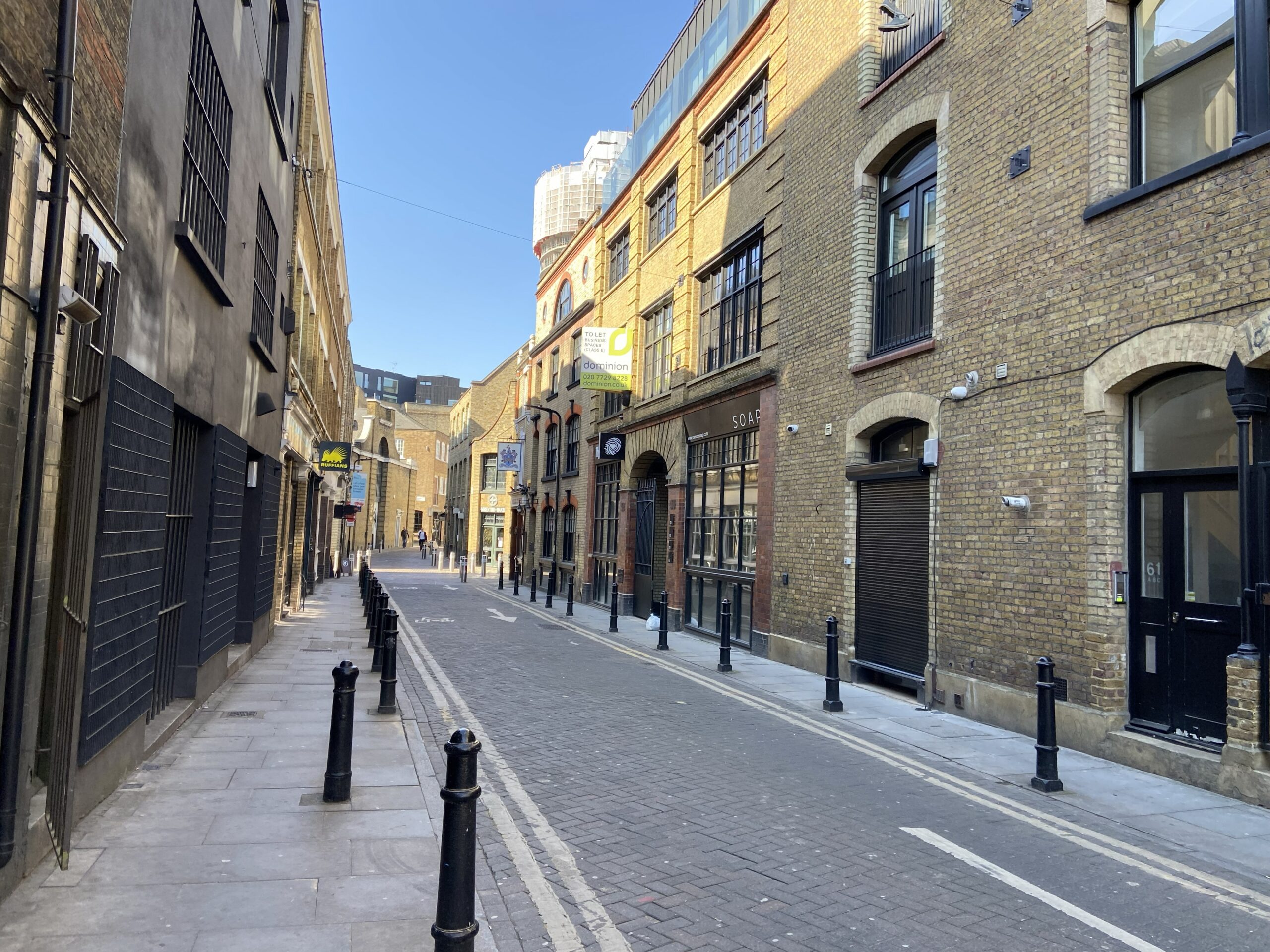 Rustig Victoriaans steegje in Shoreditch met gele bakstenen pakhuizen en zwarte paaltjes