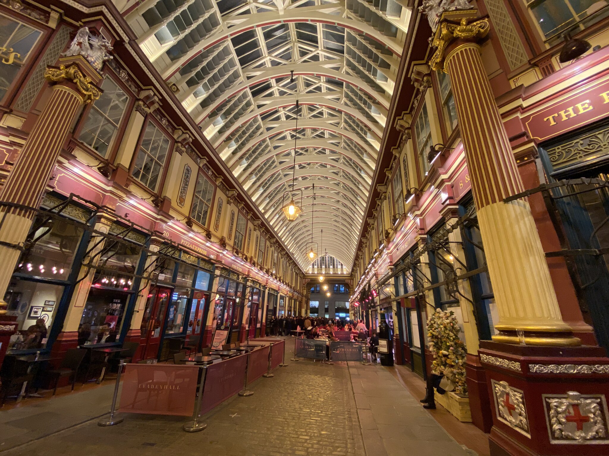 Het Victoriaanse interieur van Leadenhall Market in de City of London met de sierlijke gietijzeren overkapping in crème en bordeauxrood