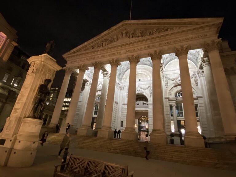 Het verlichte Royal Exchange in het hart van de City of London bij nacht, met de klassieke Griekse zuilengevel in warm licht