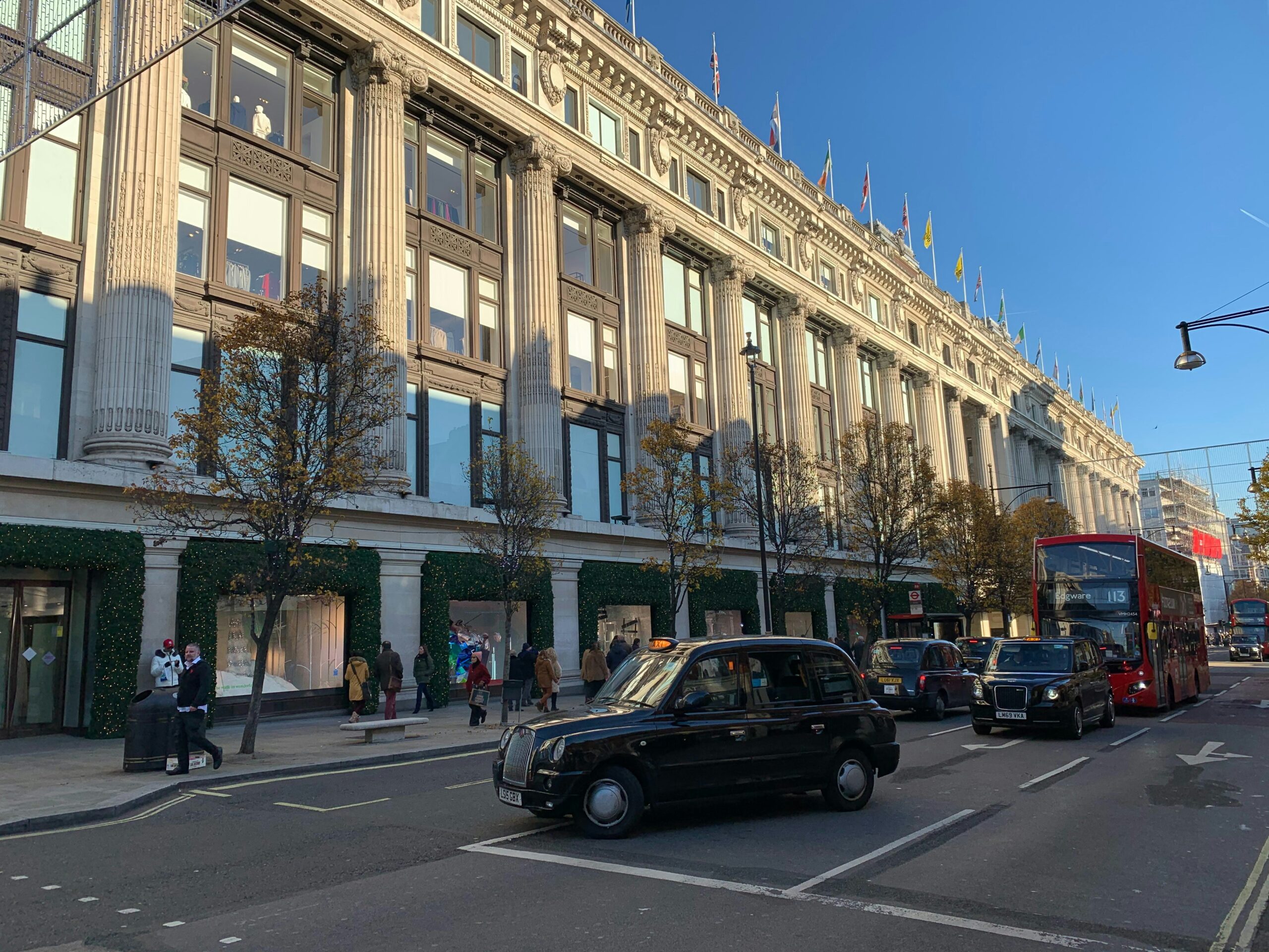 De iconische gevel van Selfridges aan Oxford Street met een zwarte Londense taxi ervoor