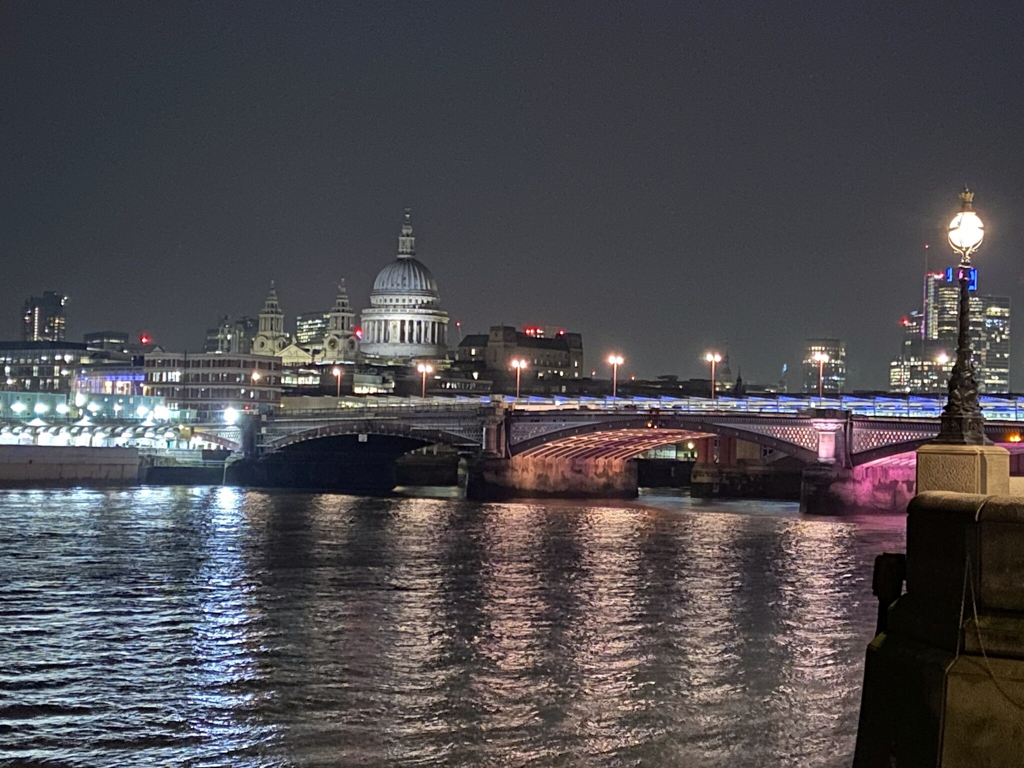 Blackfriars Bridge verlicht bij nacht met de koepel van St Paul's Cathedral op de achtergrond, gezien vanuit de South Bank