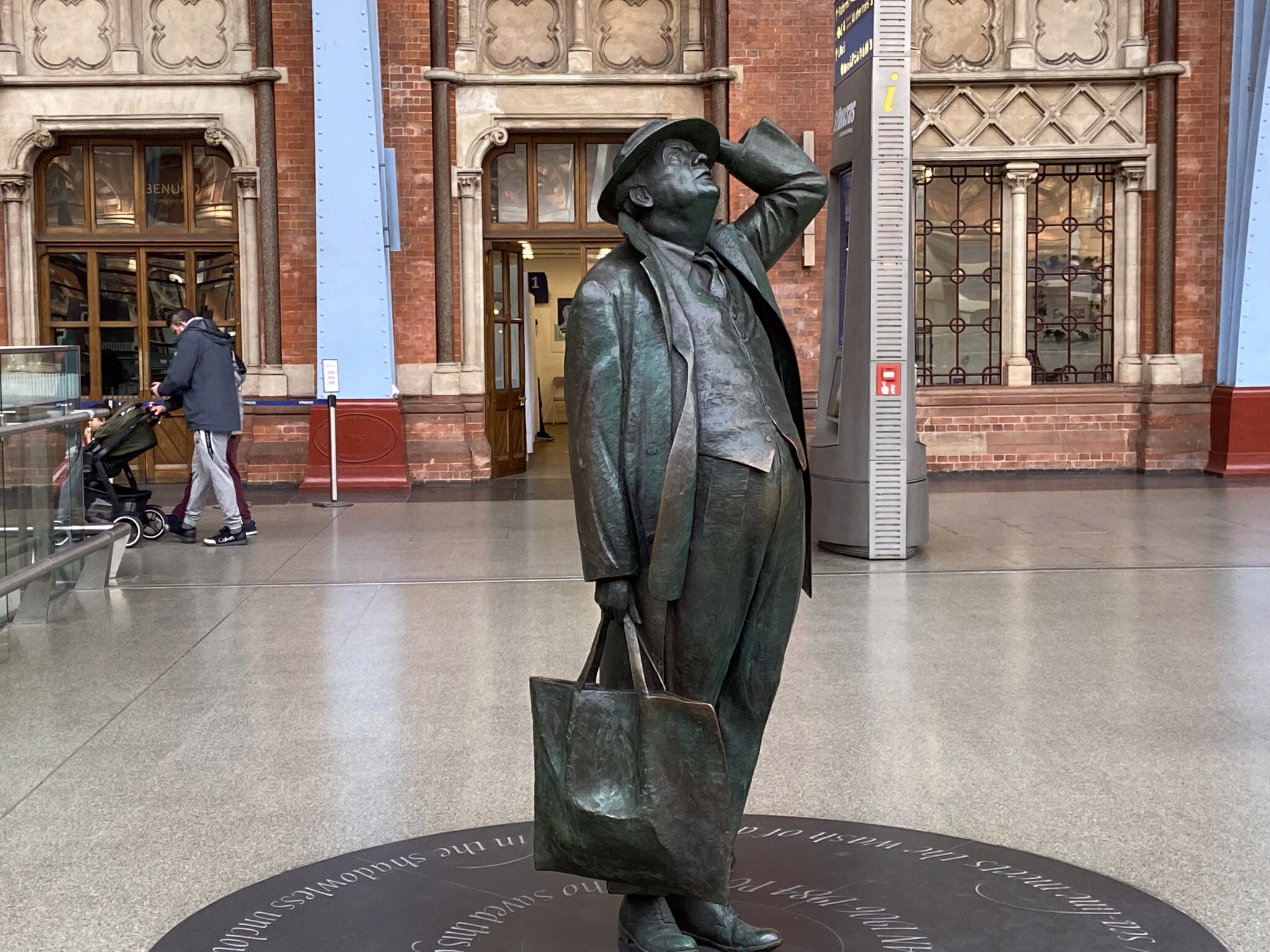Het bronzen standbeeld van dichter en conservationist Sir John Betjeman in St Pancras, omhoog starend naar het glazen dak