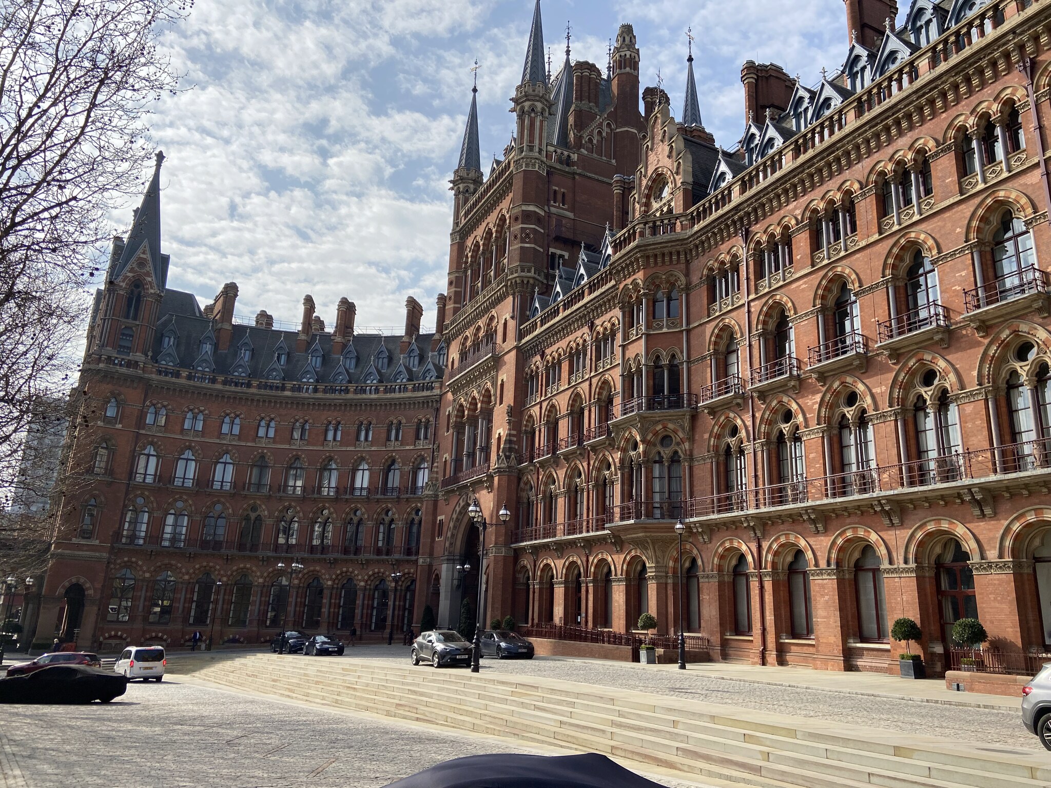 De gotische rode bakstenen gevel van het Midland Grand Hotel naast St Pancras, met Kings Cross op de achtergrond